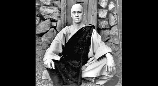 David Carradine as Kwai Chang Caine from "Kung Fu" seated on the ground in robes in front of a stone wall