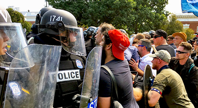 Police in riot gear hold back a crowd of men